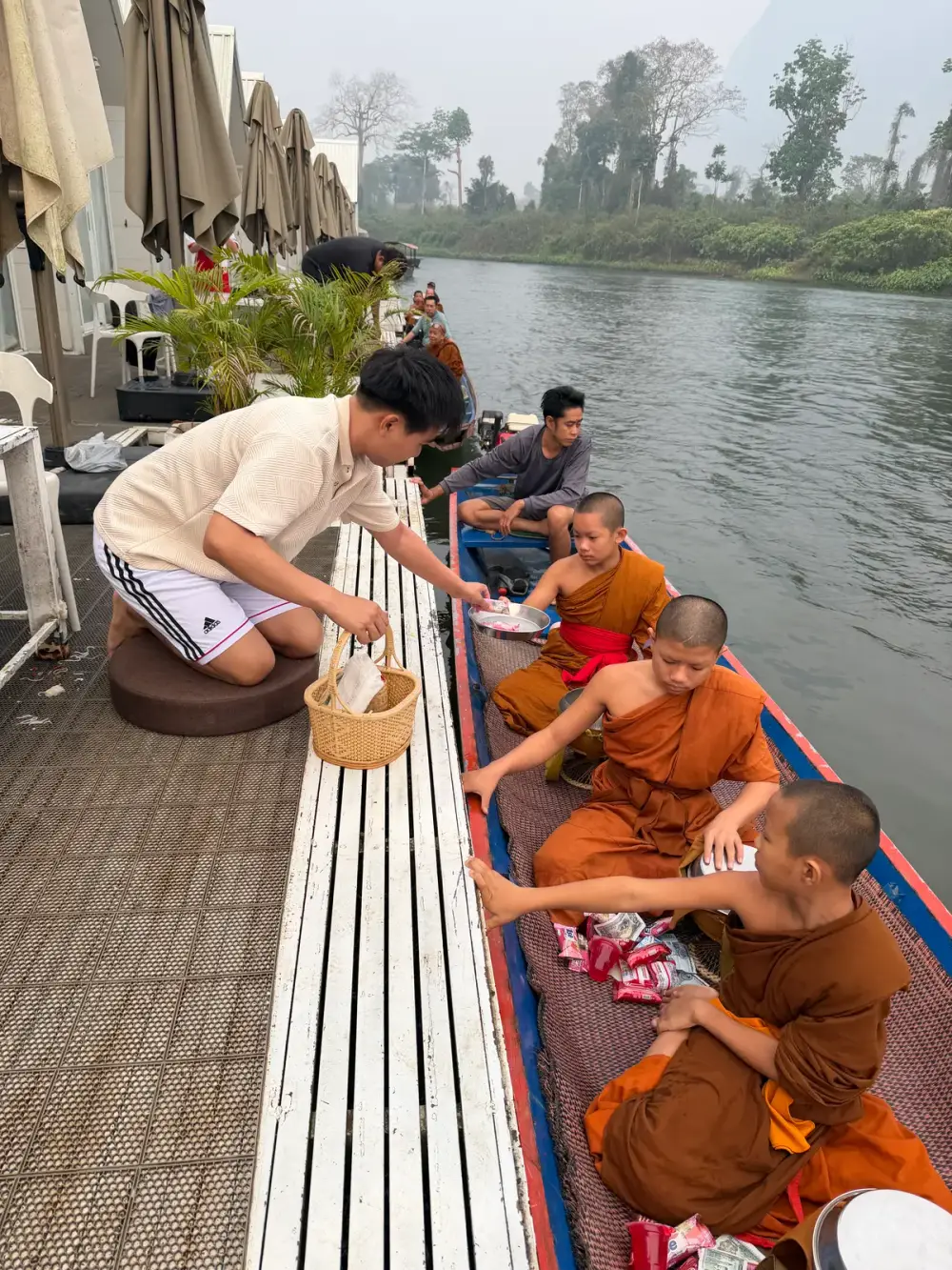 นักท่องเที่ยวใส่บาตรพระบนเรือที่แพเมืองเฟือง ยามเช้า
