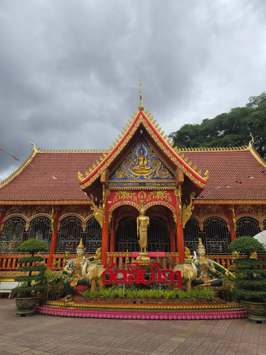 ซุ้มประตูสิมวัดสีเมืองสีแดงทอง พร้อมพระพุทธรูปยืนและป้ายชื่อวัด