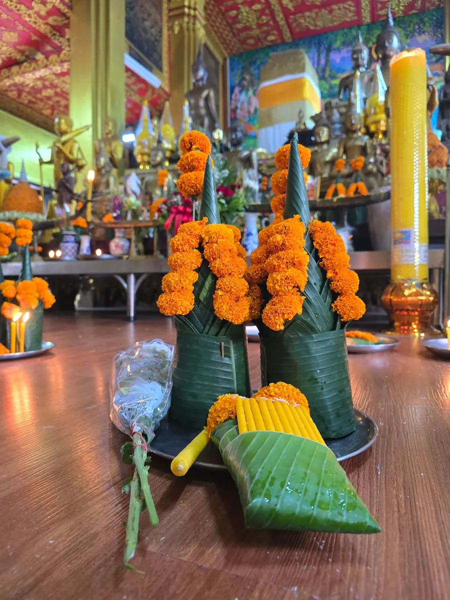 พานดอกดาวเรืองพับใบตอง ดอกไม้ และเทียนขี้ผึ้งสีเหลือง